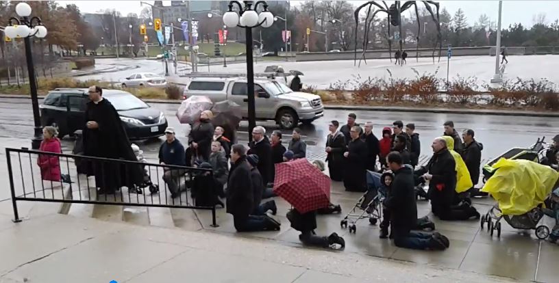 Courageous Catholics on the doorstep of a Catholic church, while Luther is warm and dry inside.